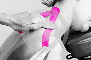 Fisiotheraphist/doctor applying cervical kinesiotape in silhouette studio on white background.