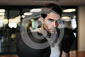 Fist full of fierceness. Portrait of a handsome man wearing sports clothing and boxing gloves and standing in boxing