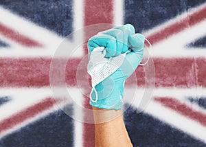 Fist hand in glove with a mask on background flag of the Great Britain.