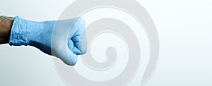 A fist in a medical glove. Doctor`s hand in a blue medical glove on a light background