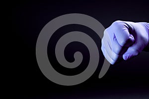 Fist of right man hand in a purple medical glove on a black background