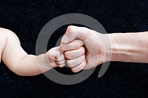 Fists of father and little son on black background