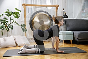 Fit active woman stretching, doing pilates and yoga fitness exercise in room at home
