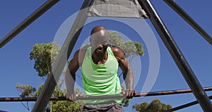 Fit african american man exercising outside, doing push ups on a climbing frame