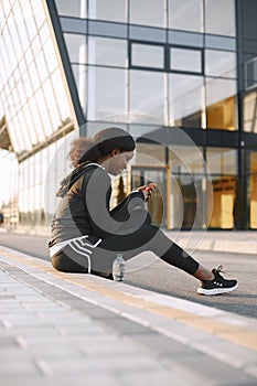 Fit african-american woman looking in a phone while training