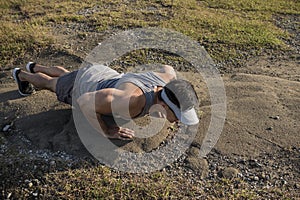 A fit asian guys does pushups on a barren rock surface after a trail run or hike in the countryside