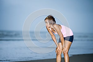 Fit Asian sport runner woman cooling off breathing after running on beach sea side looking tired while hard workout