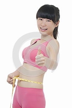 Fit Asian woman measuring her waist isolated on white background