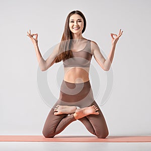 Fit asian woman in sportswear practicing yoga, keeping balance, while standing on a knees in difficult lotus pose.