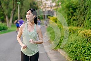 Fit Asian young woman jogging in park smiling happy running and enjoying a healthy outdoor lifestyle. Female jogger. Fitness