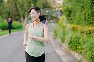 Fit Asian young woman jogging in park smiling happy running and enjoying a healthy outdoor lifestyle. Female jogger. Fitness