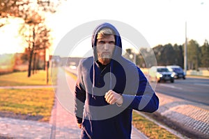 Fit athlete. Handsome adult man running outdoors to stay healthy, at sunset or sunrise. Runner.