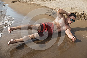 A fit an athletic asian guy does side crunches to train his obliques. Core exercise. Working out at a beach resort