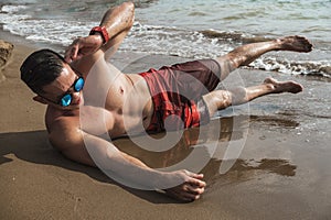 A fit an athletic asian guy does side crunches to train his obliques. Core exercise. Working out at a beach resort