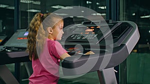 Fit Athletic Baby Girl Running on the Treadmill, Doing Her Fitness Exercise. Cute Children Actively Training in Modern