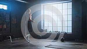 Fit Athletic Blond Woman Exercises with Jumping Rope in a Loft Style Industrial Gym. She Does Her