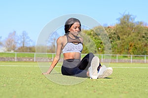 Fit athletic woman relaxing on a sports field