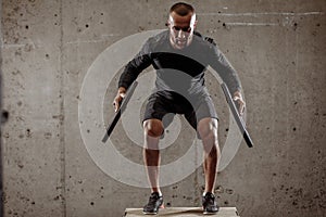 Fit athletic young man doing exercises with heavy weight barbell plate