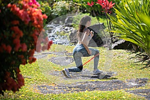 Fit back and buttocks. Athletic woman workout with resistance band outdoors.