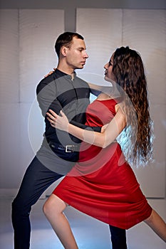 Fit ballerina and male partner dancing elements of ballroom or modern ballet in studio.