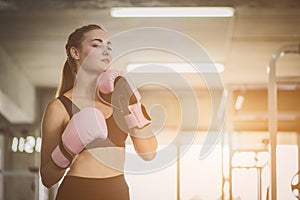 Fit beautiful woman boxer hitting a huge punching bag exercise class in a gym. Boxer woman making direct hit dynamic movement.