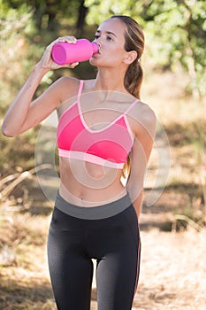 Fit beautiful woman drinking water after jogging