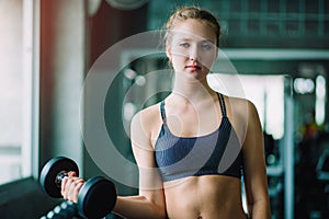 Fit beautiful young woman caucasian posing at the camera in sportswear. Young woman holding dumbbell