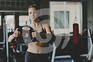 Fit beautiful young woman caucasian posing at the camera in sportswear. Young woman holding dumbbell during an exercise class