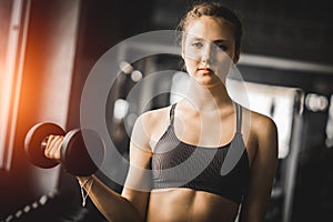 Fit beautiful young woman caucasian posing at the camera in sportswear. Young woman holding dumbbell during an exercise class gym