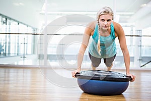 Fit blonde doing push up on bosu ball