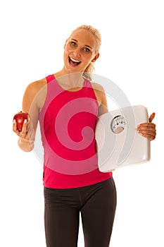 Fit blonde woman holding scale gesturing healthy lifestyle and w