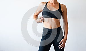 Fit body fitness girl. Slender woman in black fitness underwear standing indoors in room at daytime photo
