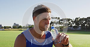 Fit caucasian man exercising outdoors, resting, drinking water