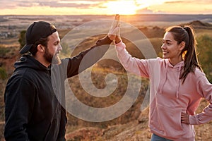 fit Couple of athletes giving high five for celebrating outdoor workout goals and success.