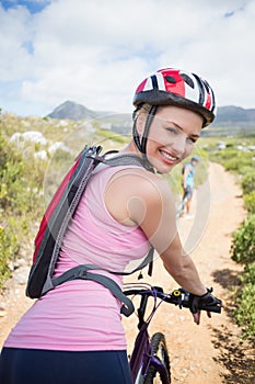 Fit couple cycling on mountain trail woman smiling at camera