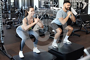 Fit couple doing jumping squats in crossfit gym