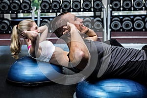 Fit couple doing sit ups on bosu ball