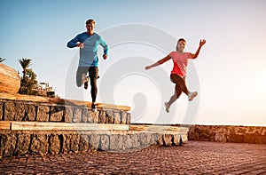 Fit couple doing workout running session at sunset outdoor - Sporty young people jogging next the beach