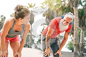 Fit couple of friends having a break after a fast race next the beach at sunset - Sporty people workout outdoor