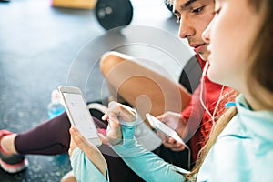 Fit couple in modern crossfit gym with smartphone.