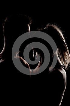 Fit couple posing together. Boy and girl side lit silhouettes on black background