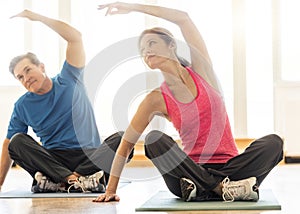 Fit Couple Practicing Yoga On Mat At Home