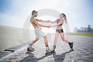 Fit couple rollerblading together on the promenade