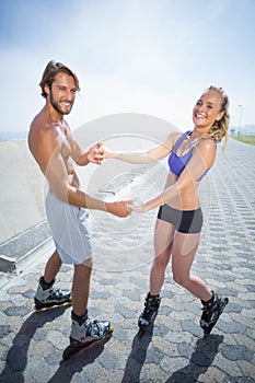 Fit couple rollerblading together on the promenade