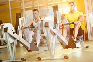 Fit couple on row machine in gym