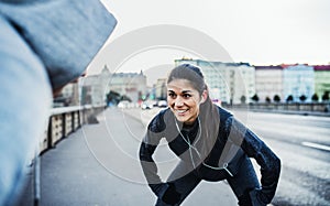 A fit couple runners stretching outdoors on the streets of Prague city.