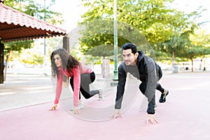 Fit couple in starting position and ready to run in the park track