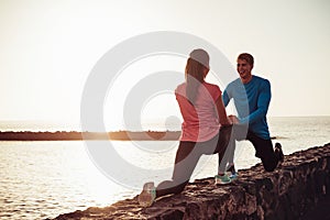 Fit couple stretching and training legs outdoor - Sporty young people doing workout session exercises next the beach