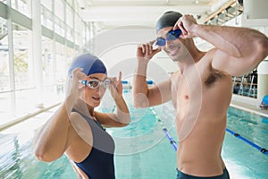 Fit couple swimmers by pool at leisure center