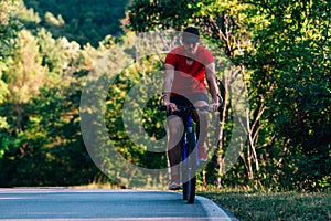Fit cyclist rides his bicycle bike on an empty road in nature